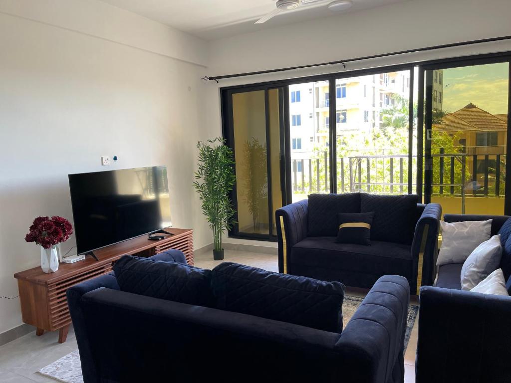 uma sala de estar com sofás e uma televisão de ecrã plano em Fortune Zone em Dar es Salaam