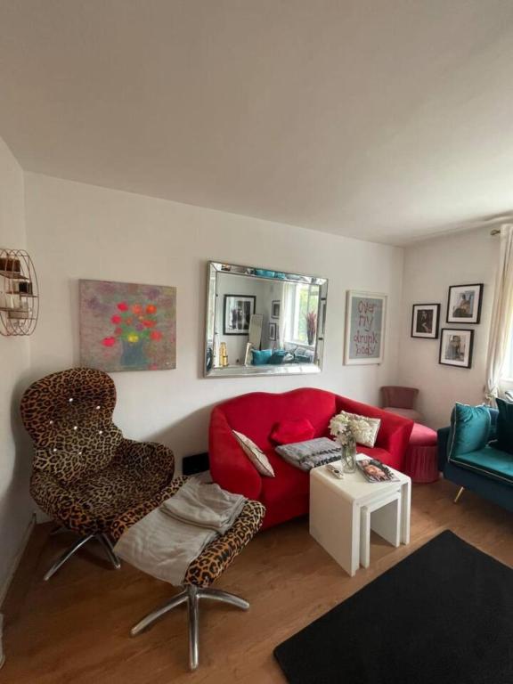 ein Wohnzimmer mit einem roten Sofa und einem Spiegel in der Unterkunft Cosy & Chic 1BD Flat - 6 Minutes to Notting Hill! in London
