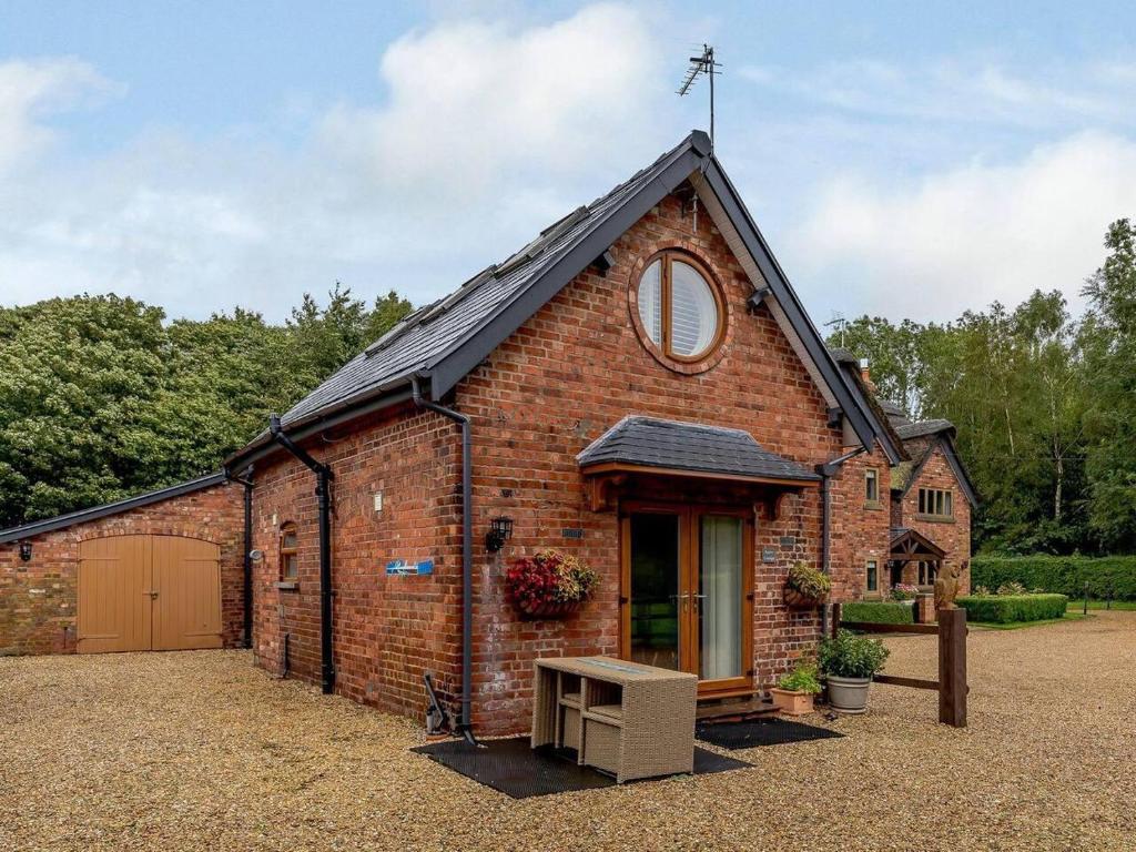 a small brick building with a window and a door at Charming 2-Bed Cottage in Toft Knutsford in Knutsford