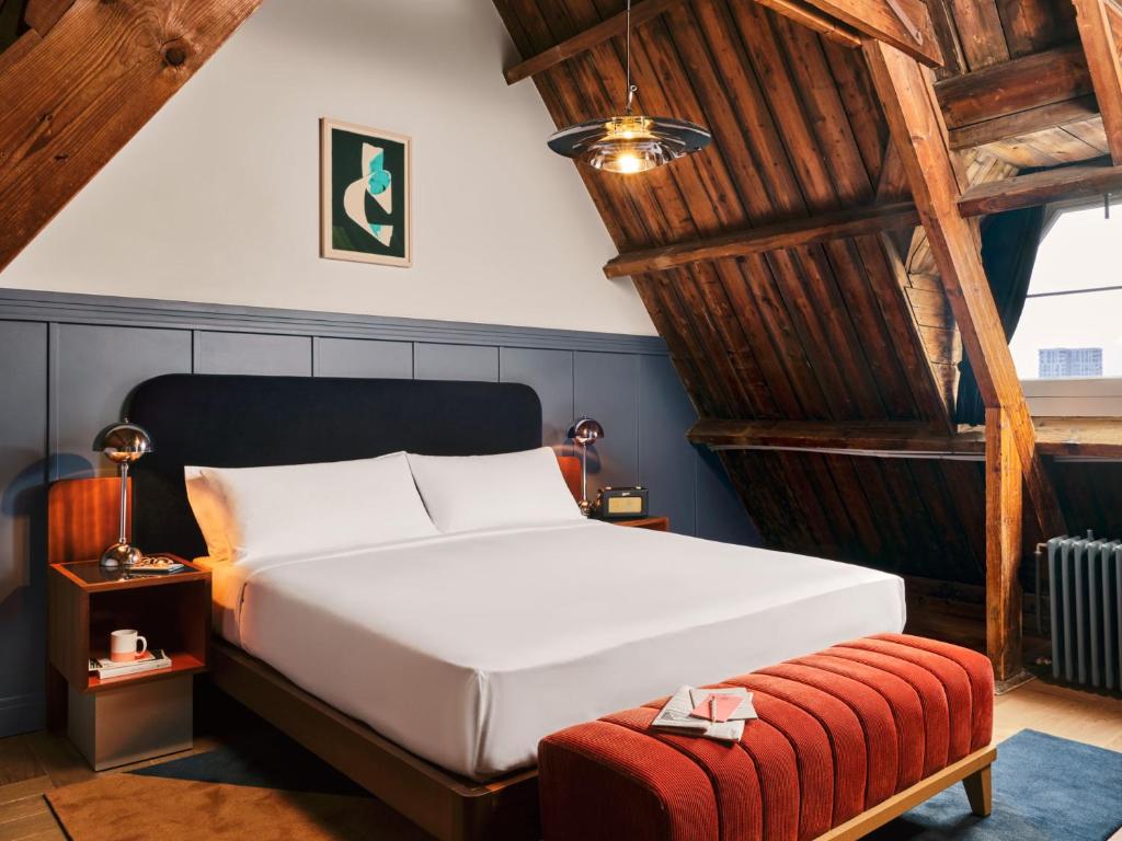 een slaapkamer met een wit bed en een rode kruk bij The Hoxton, Lloyd Amsterdam in Amsterdam