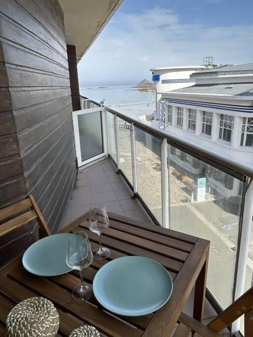 d'un balcon avec une table et des verres offrant une vue sur la plage. dans l'établissement Studio lumineux en bord de mer, à Pléneuf-Val-André