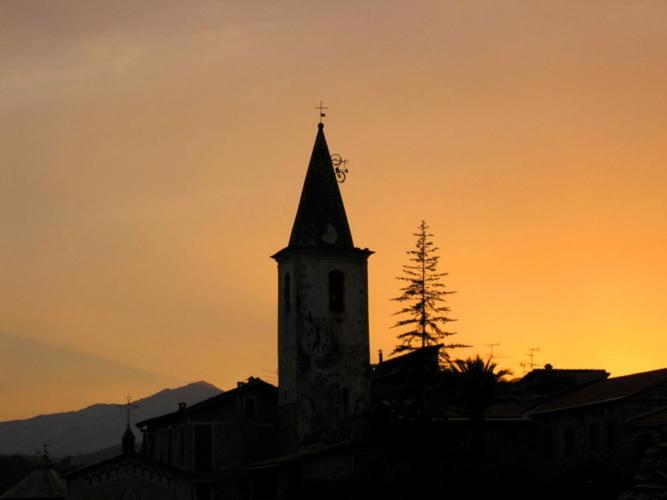 a building with a clock tower at sunset at B&B Da Giua' in Apricale