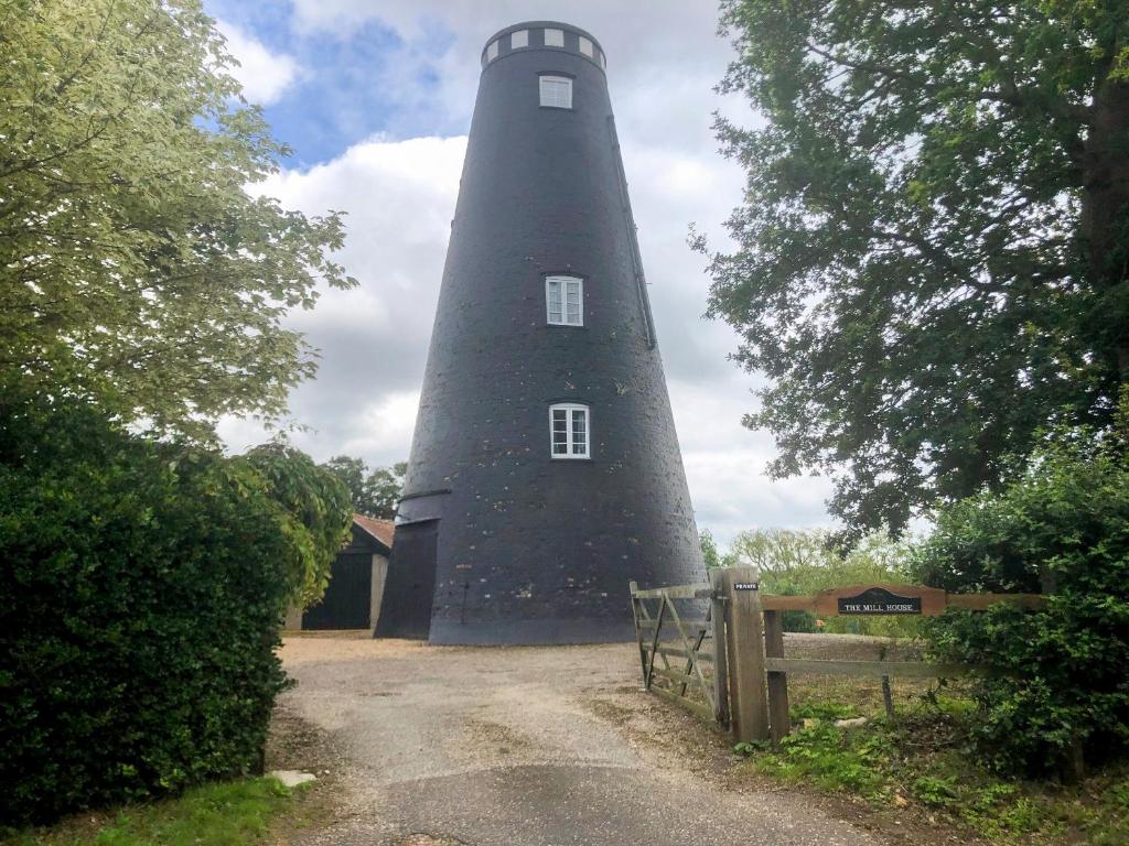 a lighthouse on a dirt road next to a fence at The Mill The Mill House in Ludham