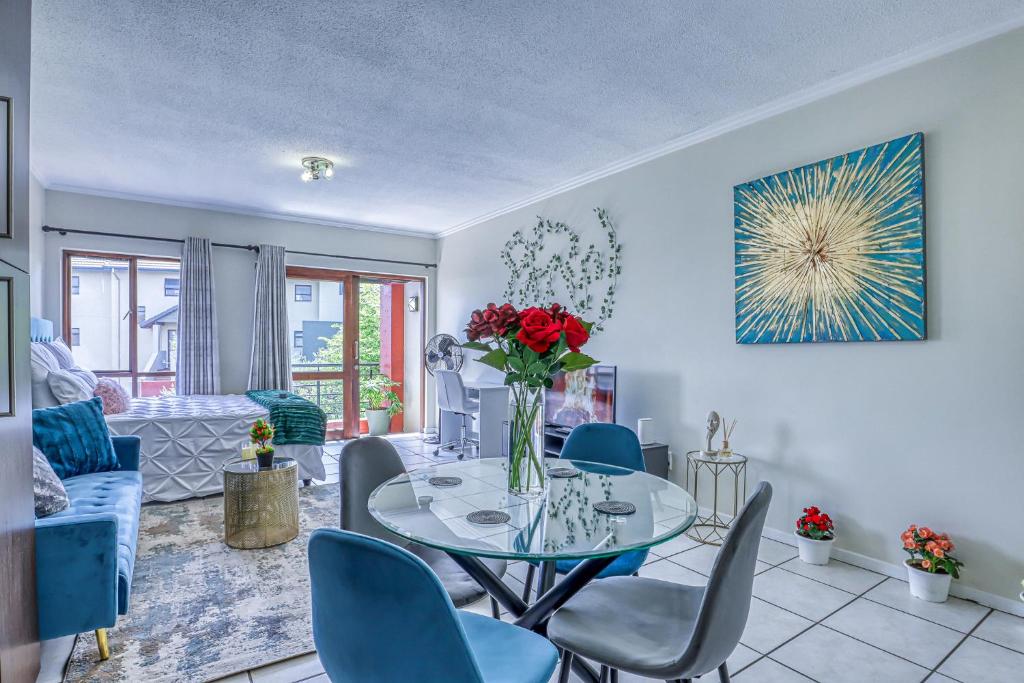 a dining room with a glass table and blue chairs at Serene Retreat on Sandton in Sandton