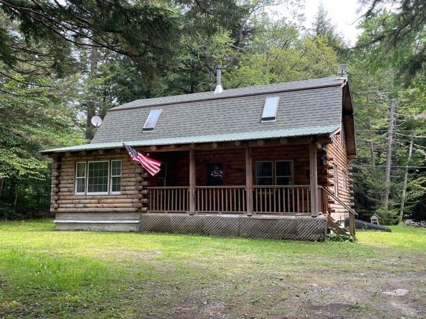 una cabaña de madera con una bandera americana delante de ella en Rustic Retreat Cozy Log Cabin, en Halifax