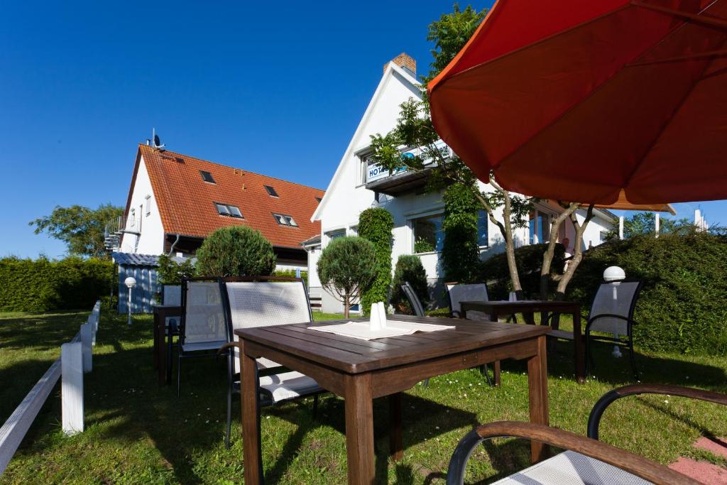a wooden table and chairs with a red umbrella at Hotel Am See in Baabe