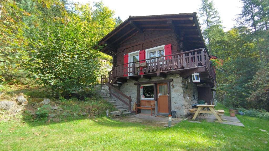 a small log cabin with a balcony and a yard at Petit chalet rustique et bucolique in Bovernier
