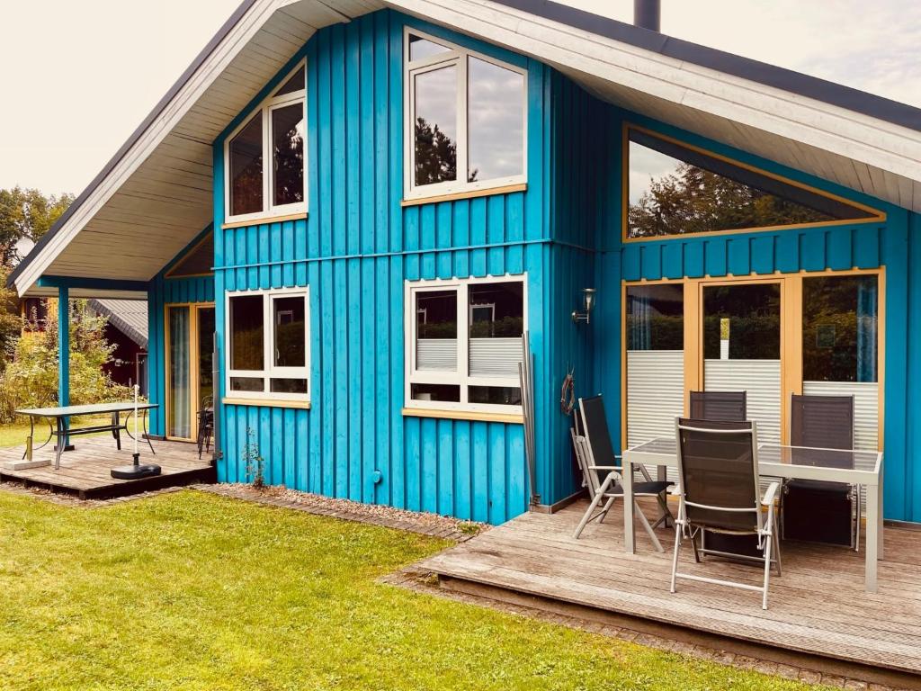 una casa azul con una mesa en la cubierta en Extertal-Ferienpark - Premium-Ferienhaus Sonnenschein #56a, en Extertal