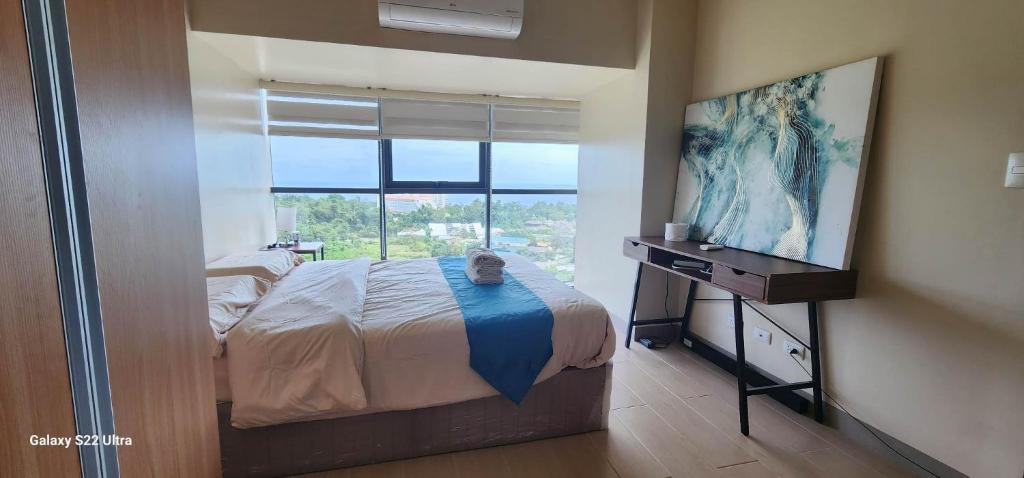 ein Schlafzimmer mit einem Bett und einem Flachbildfernseher in der Unterkunft Mactan Newtown Condo by EJB in Punta Engaño