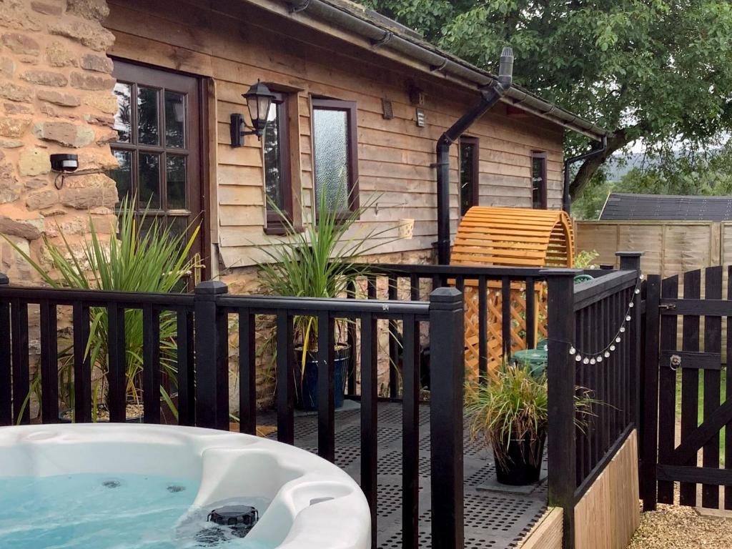 a hot tub on a deck next to a house at Newhouse Farm Barn in Neenton