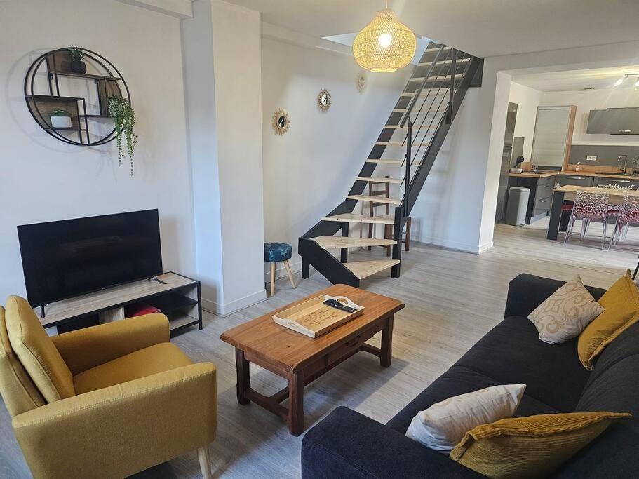 uma sala de estar com um sofá, uma mesa e uma escada em L'Estran em Dieppe