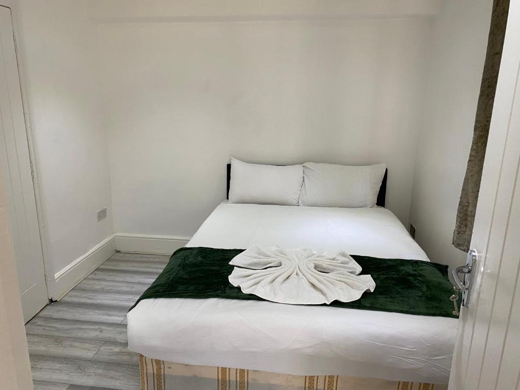 a bedroom with a white bed with a green blanket at W3 Guest House in London