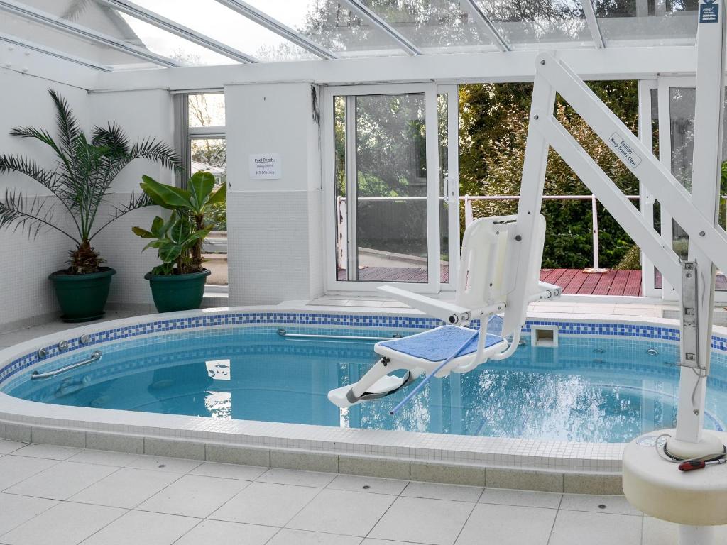a swimming pool with two chairs in a house at Riverside in Bude