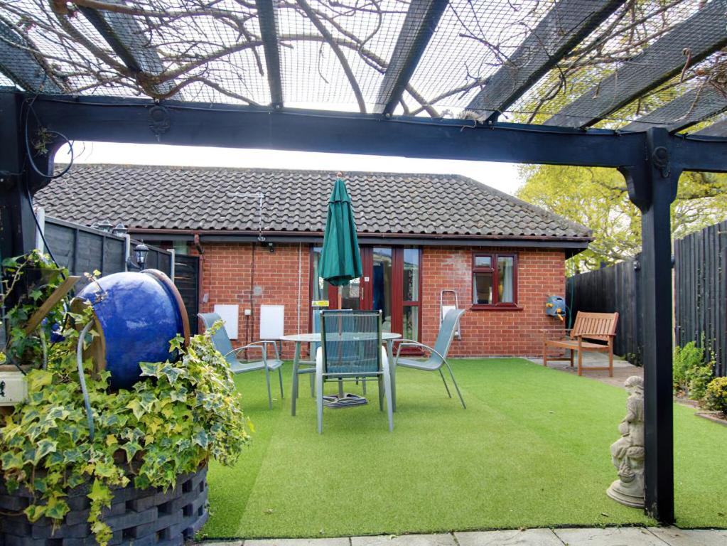 een patio met een tafel en een groene parasol bij Irenic Lodge 2 in Netley