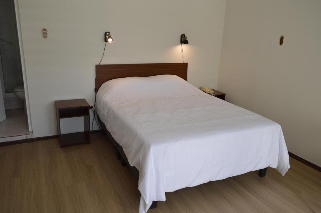 sypialnia z łóżkiem z białą narzutą w obiekcie Hotel Rukalaf w mieście Chillán