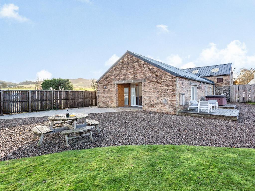 a brick house with a picnic table and a patio at Woodend Barn in Auchterarder