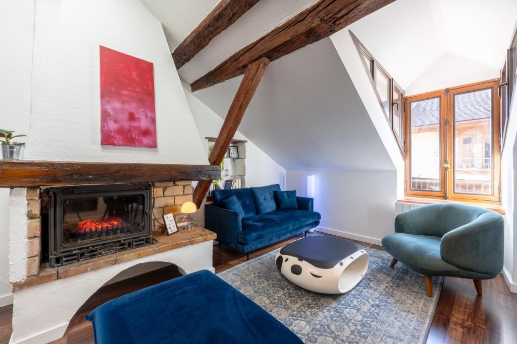 a living room with a fireplace and blue chairs at Sous Les Toits d'Annecy, un appartement irrésistible pour 1 à 6 personnes en plein coeur de ville in Annecy