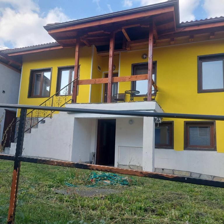 a yellow and white house with a porch at Guest Rooms Didka in Koprivshtitsa