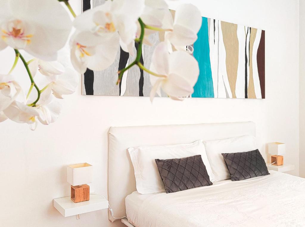 1 dormitorio con 1 cama blanca con flores blancas en Corte Melone room rental, en Verona