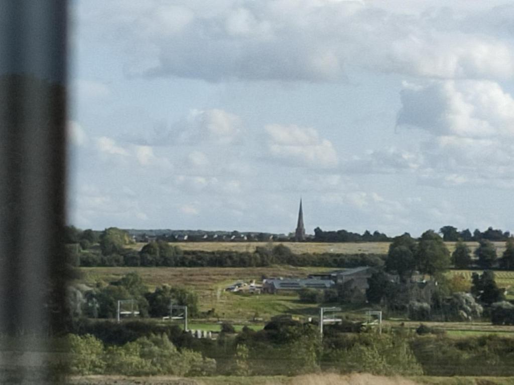 een uitzicht op een veld met een kerktoren in de verte bij Homeaway in Wellingborough