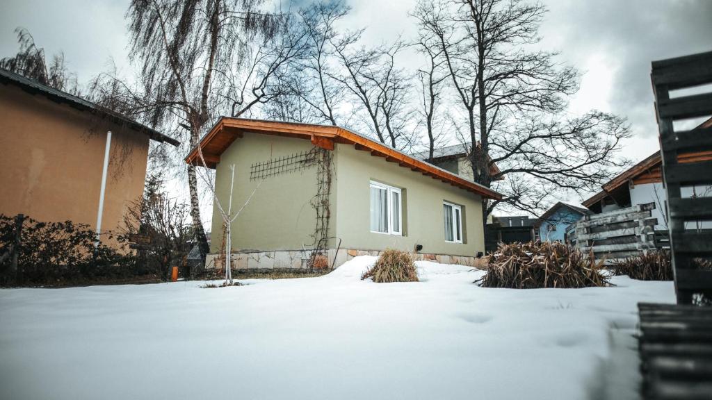 una pequeña casa con nieve en el suelo en Sombra Verde en Villa La Angostura