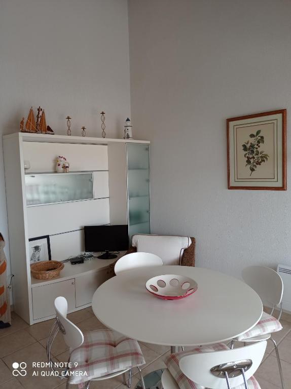 une salle à manger blanche avec une table et des chaises dans l'établissement Ombre et soleil vue sur la lagune et bateaux, à Saint-Cyprien