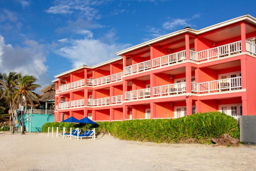 ein rotes Gebäude am Strand mit Palmen in der Unterkunft Mayan Princess Hotel in San Pedro