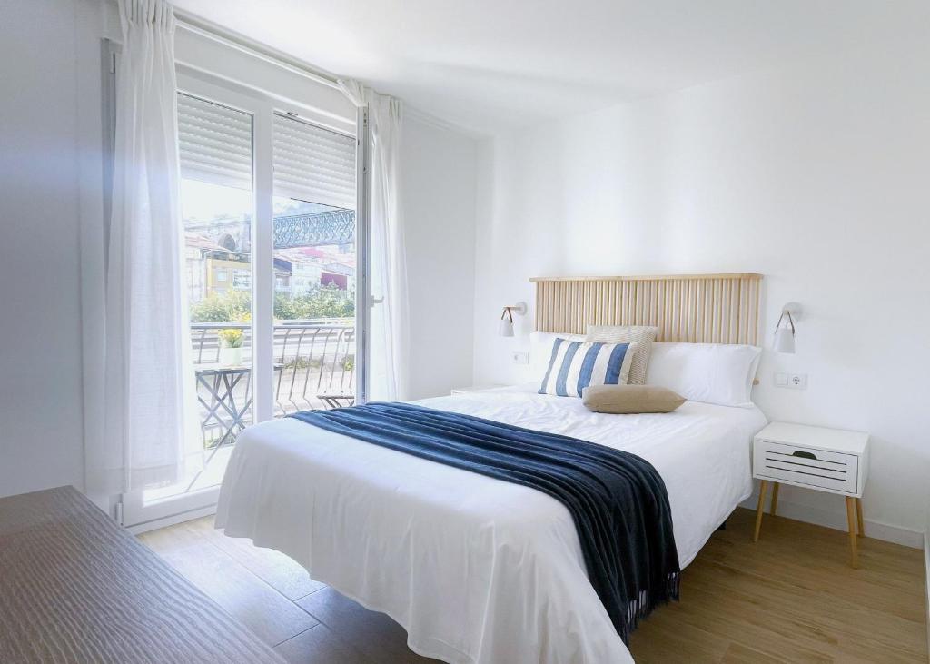 a white bedroom with a large bed and a window at A Marisma Hostal in Redondela