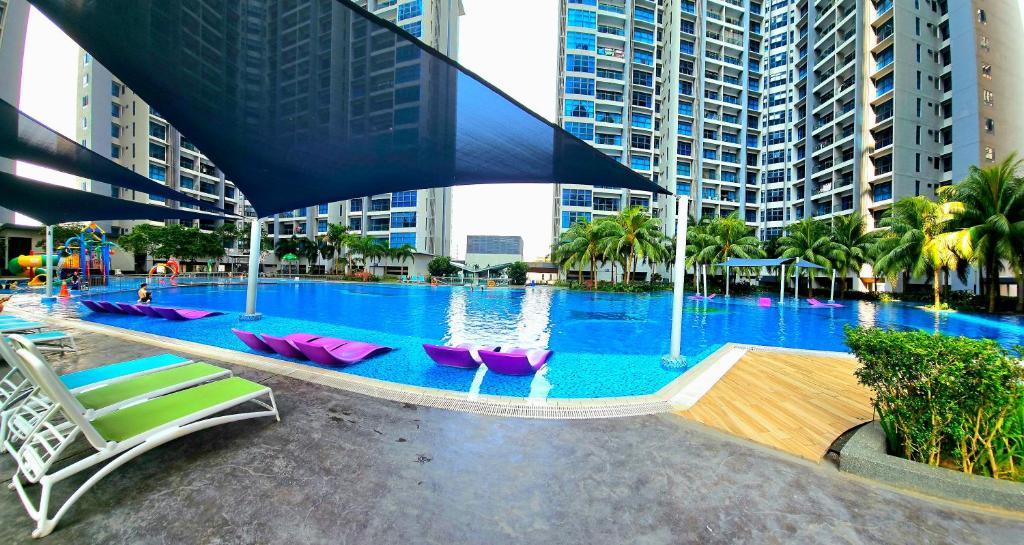 a large swimming pool with pink chairs and buildings at Atlantis Residence @ Melaka in Melaka