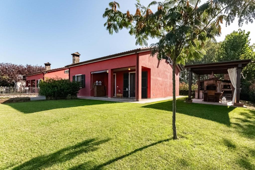 una casa roja con un árbol en el patio en Villa Luxury - Sarzana, en Luni