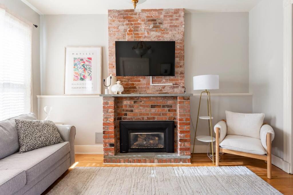 a living room with a brick fireplace with a tv at The Matisse at Wooster Square Yale with Parking in New Haven