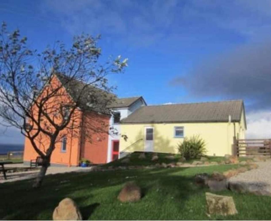 a white house with a tree and a building at Princes point villa all on ground floor in Portree