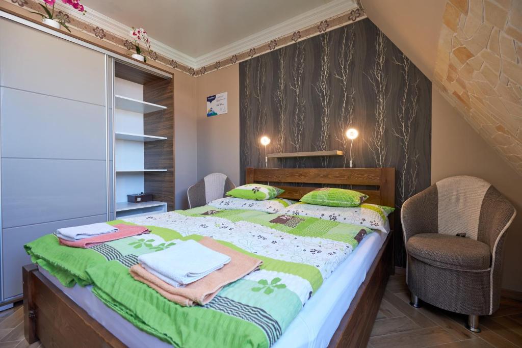 sypialnia z łóżkiem z zielonymi kocami i krzesłem w obiekcie Valentin Deluxe Apartman w Hajduszoboszlo