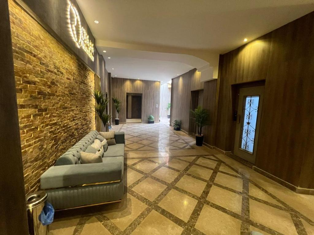 a lobby with a couch and a brick wall at Rotana Palace Suites in Cairo