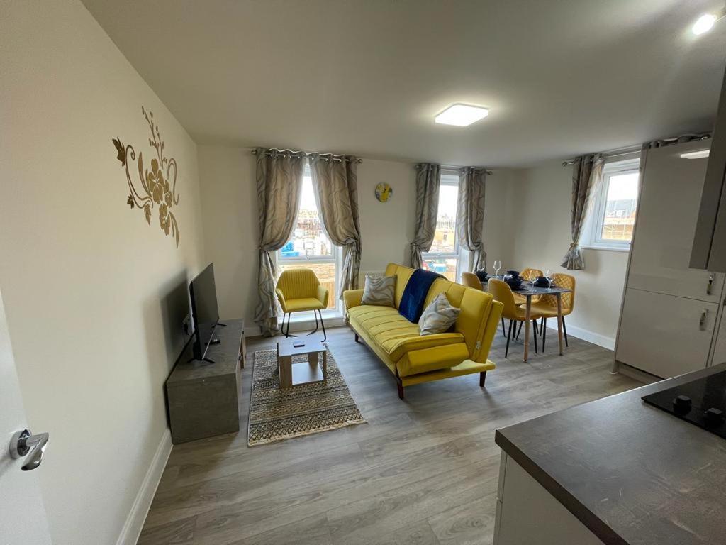 a living room with a yellow couch and a table at Spacious Apartment in Brooklands in Milton Keynes