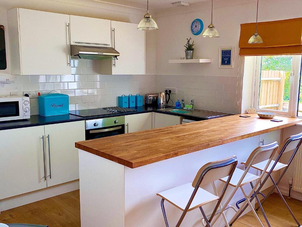 a kitchen with white cabinets and a wooden counter top at Weavers Lodge in Ibsley