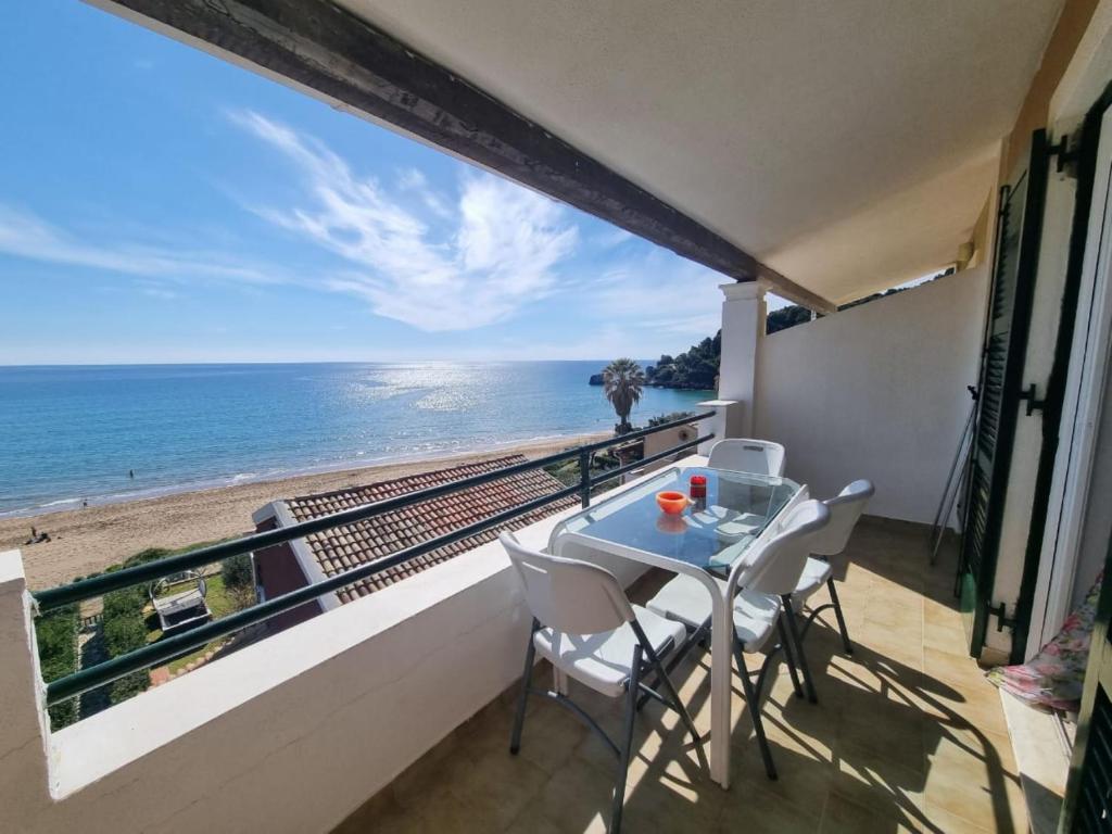 a balcony with a table and chairs and the ocean at Corfu Dream Holidays Villas in Glyfada