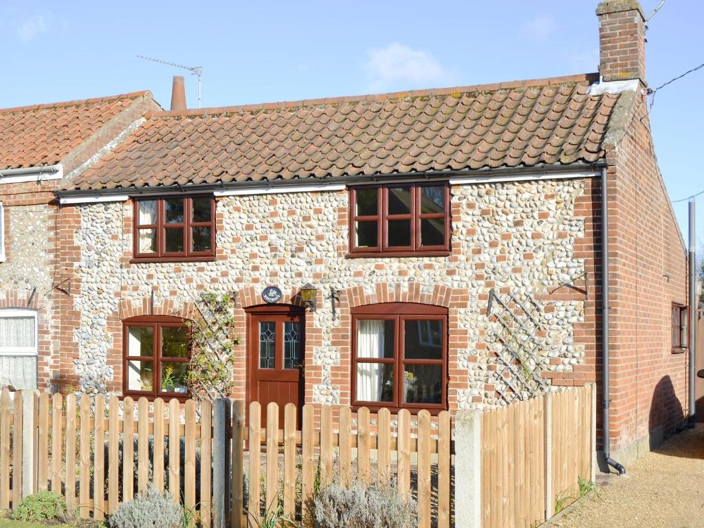 a brick house with a wooden fence in front of it at Heathcote Cottage in Hickling