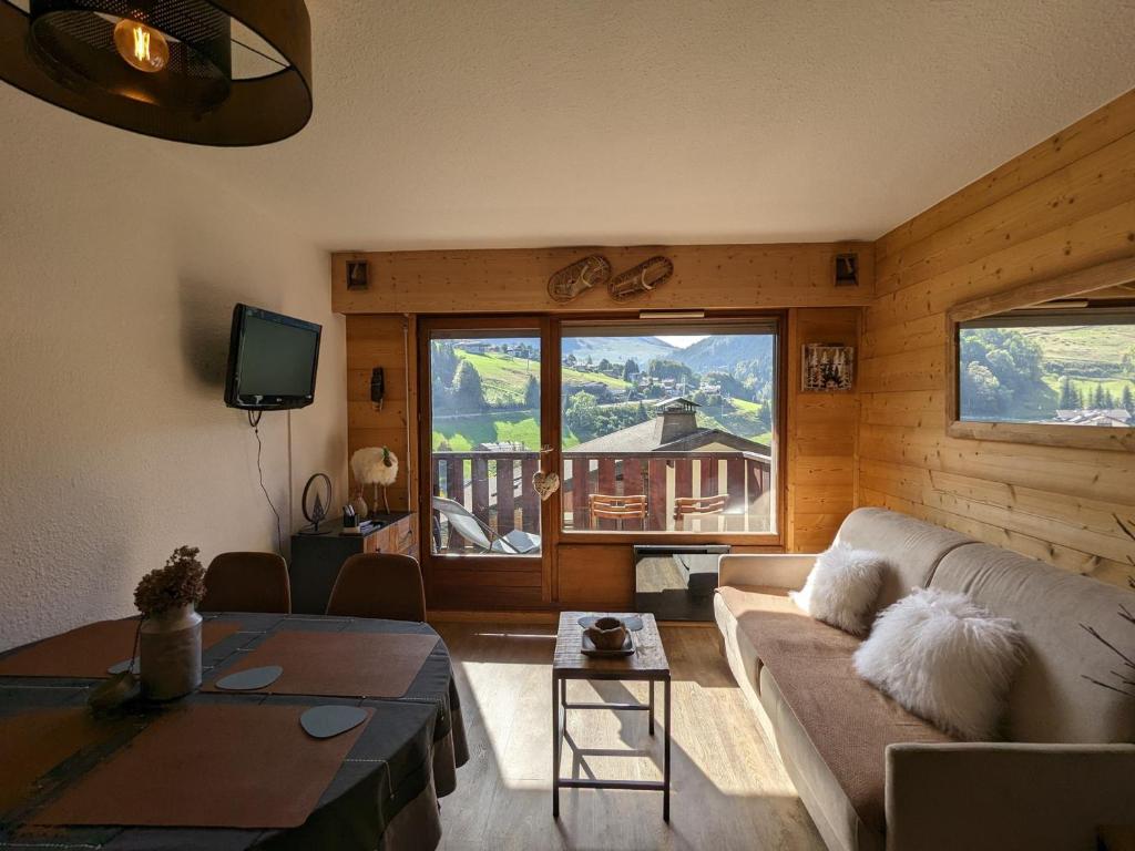 un salon avec un canapé et une table dans l'établissement Appartement rénové 2023 au centre de La Clusaz avec balcon, garage, et accès facile aux pistes - FR-1-459-178, à La Clusaz