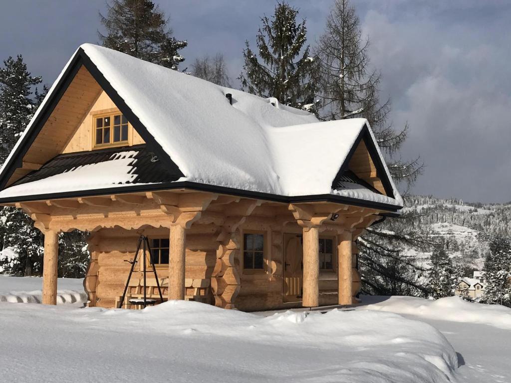 ein Blockhaus mit einem schneebedeckten Dach in der Unterkunft Agroturystyka "Na Zogrodzie" Alicja Kowalczyk in Harklowa