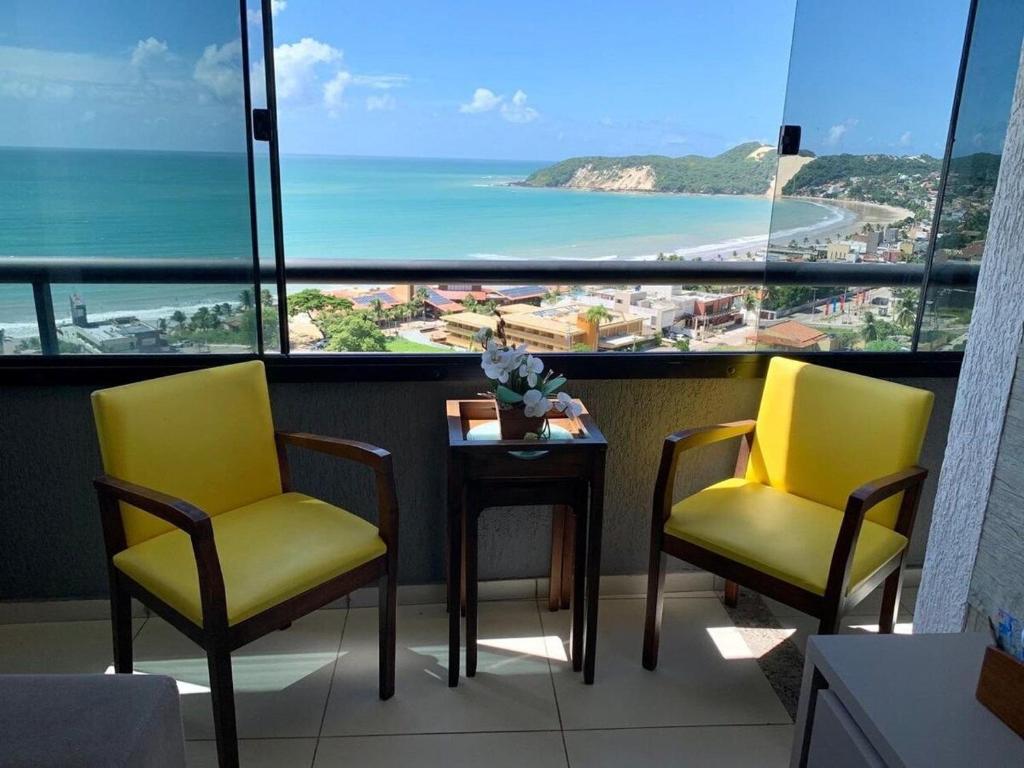 2 stoelen en een tafel in een kamer met uitzicht op de oceaan bij Duas suítes com a melhor vista de Ponta Negra! in Natal