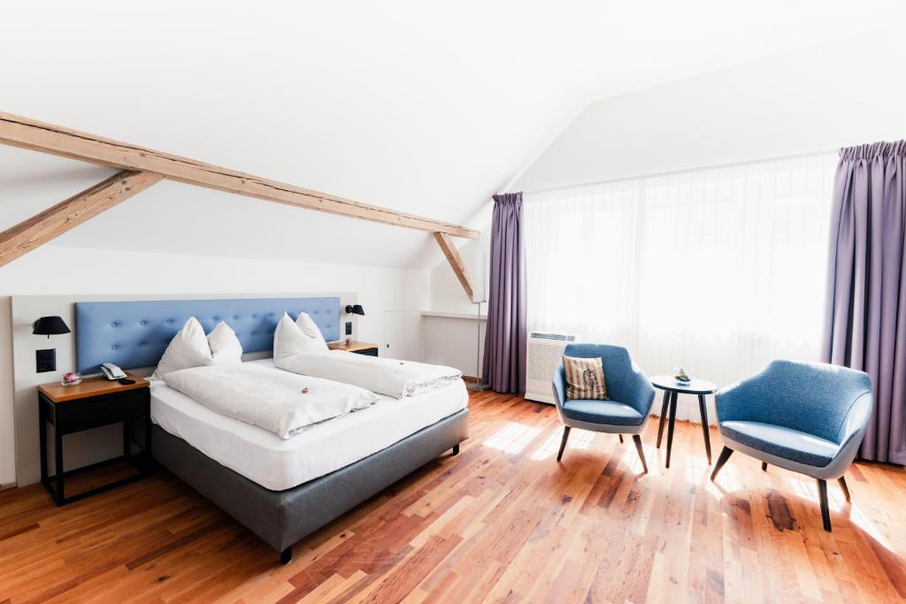 a bedroom with a bed and two chairs at Landgasthof Leuen in Uitikon