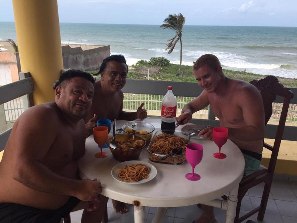Eine Gruppe Männer, die an einem Tisch sitzen und Essen essen. in der Unterkunft Pousada e Hostel Lua de Tomate in Caucaia