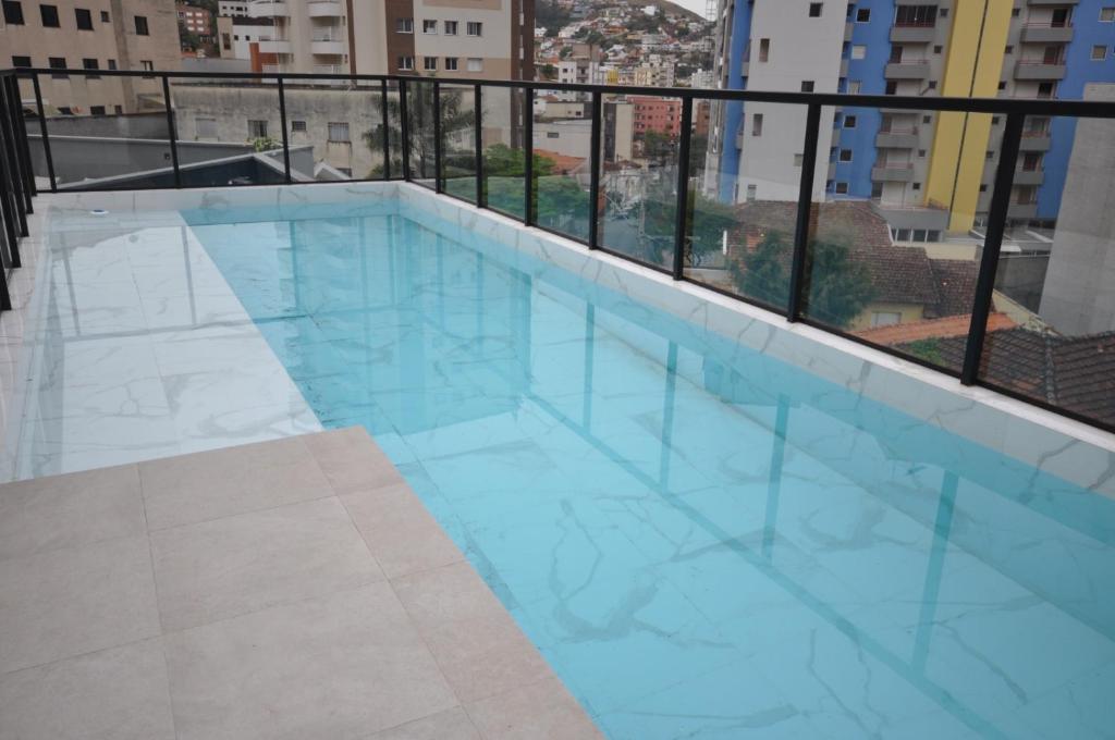 a large blue swimming pool on top of a building at Studio no centro in Poços de Caldas