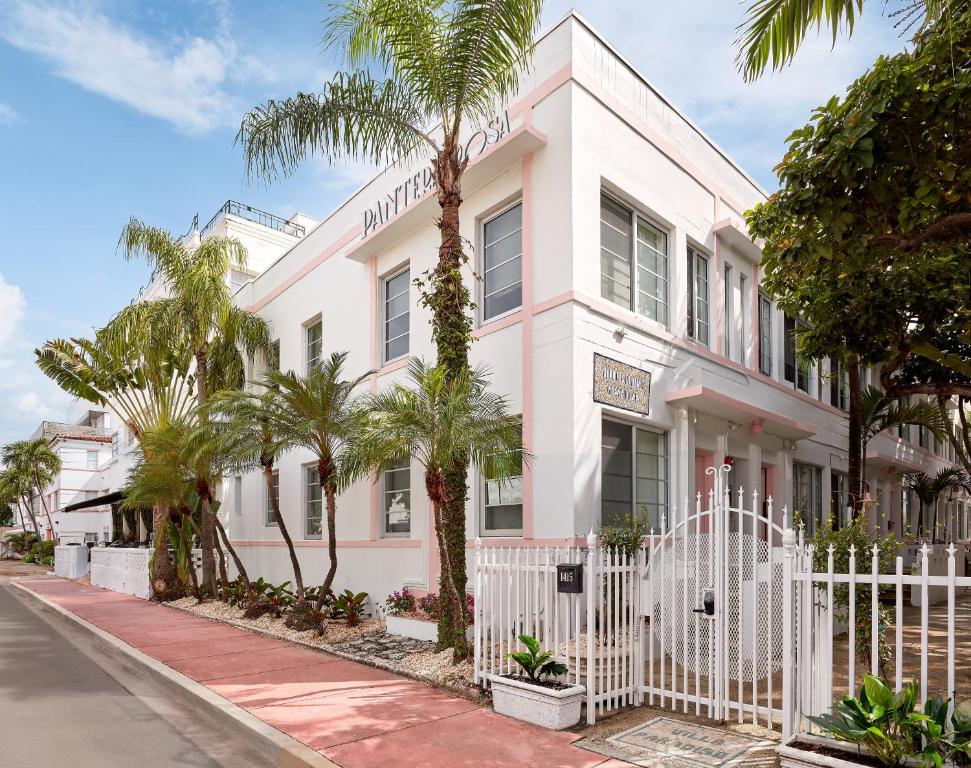 a white building with palm trees in front of it at Pantera Rosa in Miami Beach