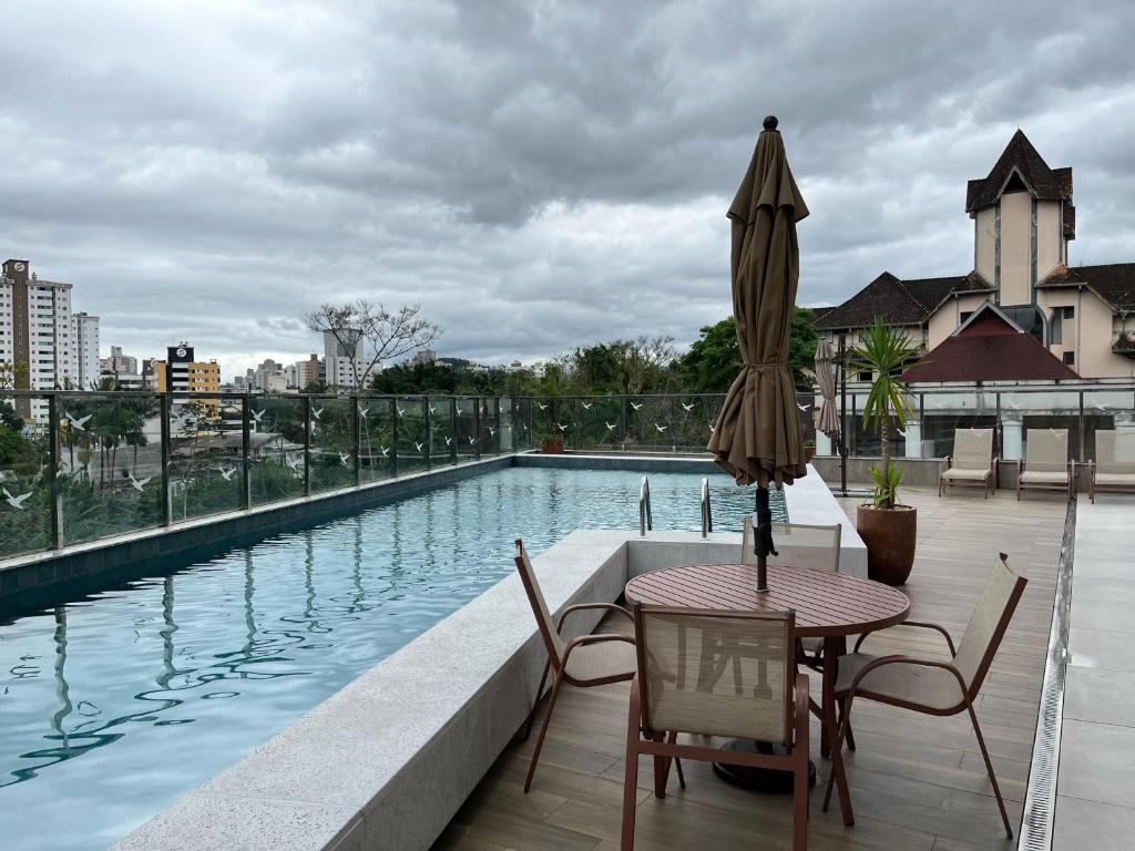 a patio with a table and an umbrella next to a pool at House Park completo em Blumenau-SC in Blumenau
