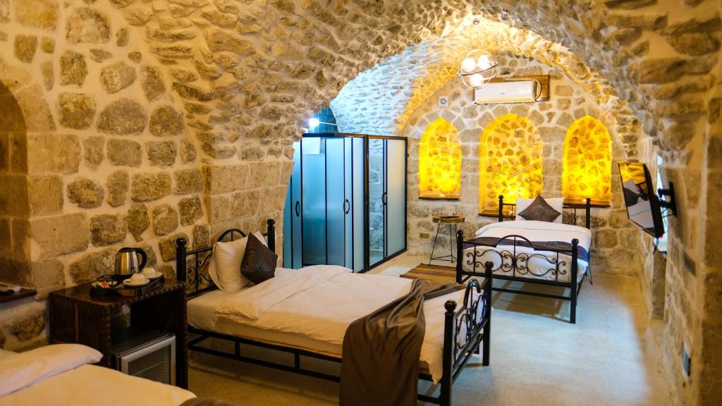 a room with two beds in a stone wall at AĞA KONAĞI HOTEL in Mardin