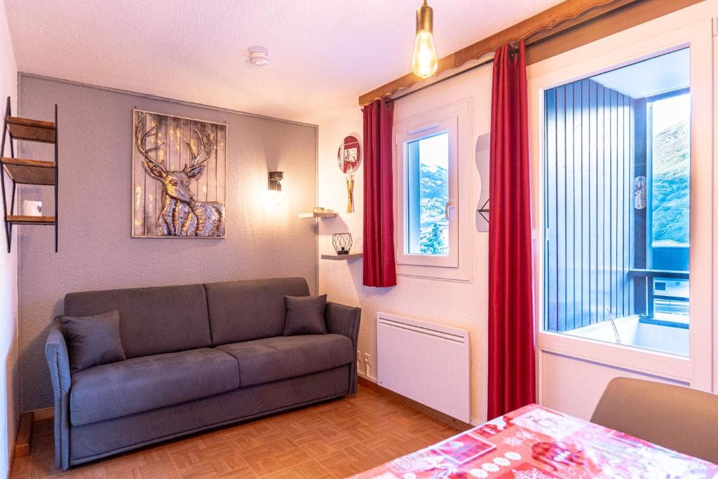 ein Wohnzimmer mit einem Sofa und einem Fenster in der Unterkunft Les gentianes 311 in Les Menuires
