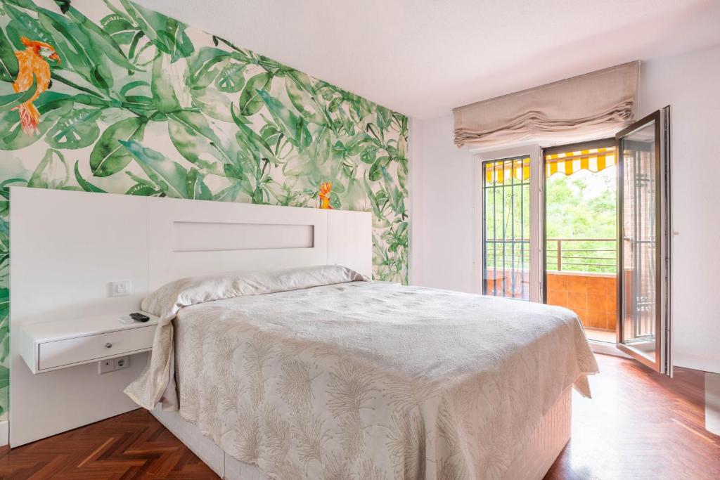 1 dormitorio con 1 cama con papel pintado tropical en Bonita habitación con balcón, en Villaviciosa de Odón