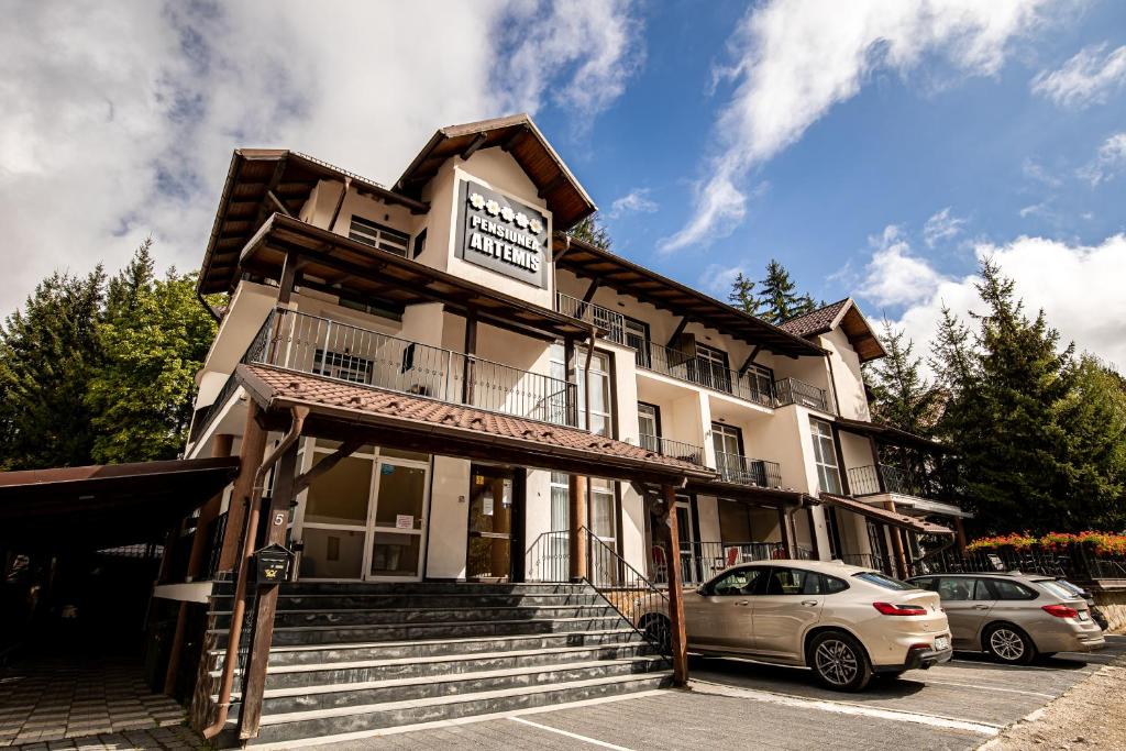a building with a car parked in front of it at Artemis Villa in Poiana Brasov